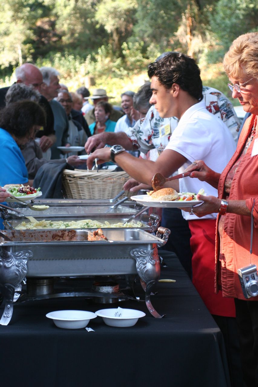 Caterer employee replenishing food buffet
